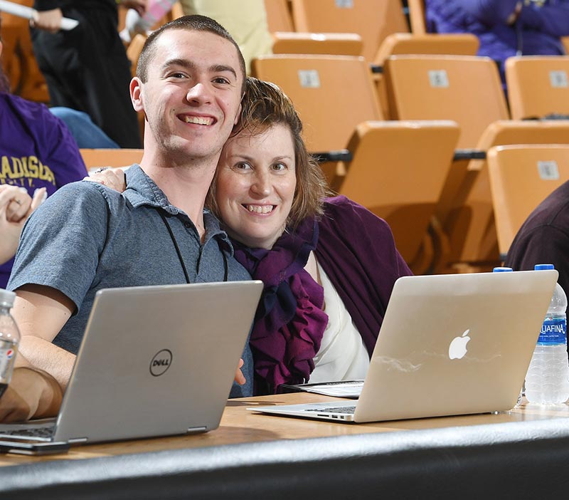 Vicki and her son, Harry, both working a basketball game together on press row at James Madison University. 